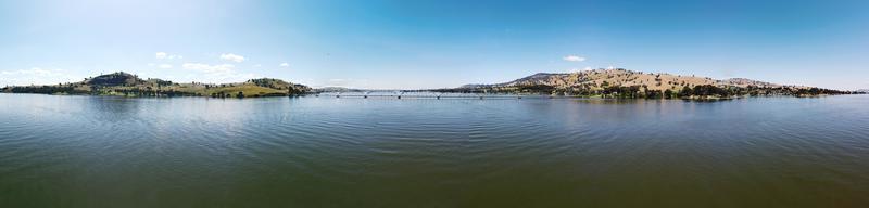 Fotografia de 360 graus com vista para o lago hume é a pitoresca cidade de bellbridge, oferecendo vistas da vizinha ponte bethanga em albury nsw, austrália, a água calma filmada por drone. foto