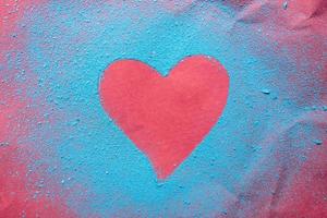 Dia dos Namorados. coração vermelho - um símbolo de amor polvilhado com pó azul brilhante, sobre um fundo texturizado brilhante. conceito romantico.. foto