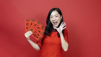 mulher asiática segurando o envelope da fortuna de dinheiro vermelho abençoando a palavra chinesa, o que significa que você pode ter muita sorte e grande lucro isolado em fundo vermelho para o conceito de celebração do ano novo chinês foto