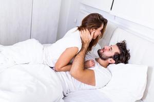 lindo casal apaixonado beijando na cama. lindo casal jovem deitado juntos na cama. casal jovem romântico apaixonado, deitado na cama. lindo casal sorrindo na cama. foto