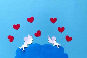 conceito de dia dos namorados. corações vermelhos e cupido mirando no coração sobre fundo azul. cartão de dia dos namorados criativo. foto
