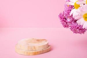 pódio de madeira ou pedestal com flores de crisântemo em fundo rosa. maquete para seus produtos cosméticos foto
