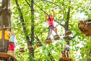 crianças felizes em um parque de corda no fundo de madeira foto