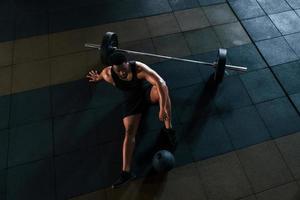 sentado no chão. homem afro-americano forte em roupas esportivas tem dia de treino na academia foto