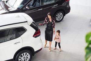 mãe com sua filha caminhando juntos perto de automóvel moderno dentro de casa foto