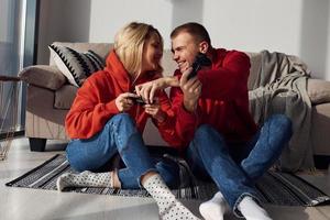 jovem casal adorável juntos em casa jogando videogame no fim de semana e feriados juntos foto