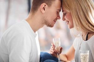 jovem casal adorável juntos em casa com champanhe passando fim de semana e feriados juntos foto