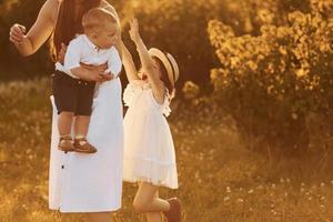 família feliz de mãe, filho e filha passar o tempo livre no campo em dia ensolarado de verão foto