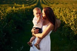 mãe positiva com seu filho passando o tempo livre no campo no dia ensolarado do verão foto