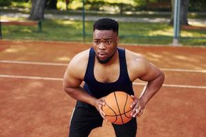 homem afro-americano joga basquete na quadra ao ar livre foto