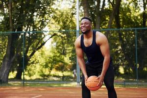 homem afro-americano com garota joga basquete na quadra ao ar livre foto