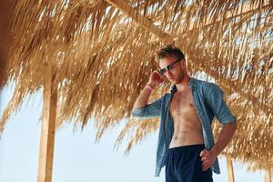 posando para uma câmera. jovem europeu tem férias e aproveita o tempo livre na praia do mar foto