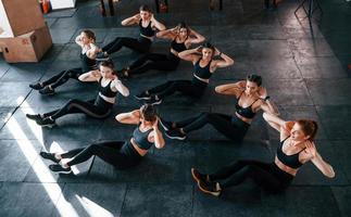 fazendo abdominais. grupo de jovens esportivos tem dia crossfit dentro de casa na academia foto