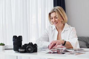 mulher de meia-idade em roupas elegantes está em casa. fotógrafo com câmera foto