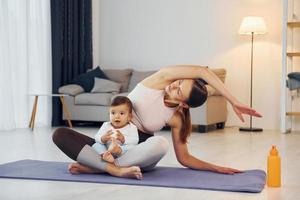fazendo exercícios de ioga. mãe com sua filha está em casa juntos foto