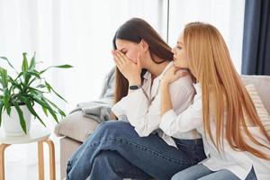 mulher está chorando. jovem mãe com sua filha está em casa durante o dia foto