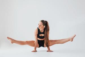 corpo bonito. jovem em roupas esportivas fazendo ginástica dentro de casa foto