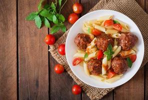 macarrão penne com almôndegas em molho de tomate em uma tigela branca foto