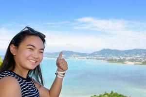 turista de mulher levantando elogios de polegar lindo do mar em phuket, tailândia foto