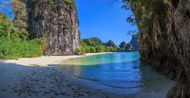 vista sobre a praia tropical com palmeiras e rochas imponentes na tailândia foto