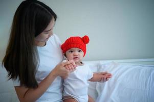 mãe e bebê recém-nascido usando chapéus vermelhos no quarto branco, sol quente à noite do dia foto