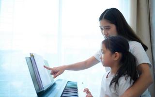 férias em família, outros ajudando a filha a praticar em suas aulas de piano foto