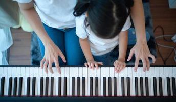 férias em família, outros ajudando a filha a praticar em suas aulas de piano foto