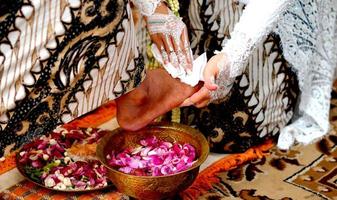 tradição de casamento na indonésia a noiva lava os pés do noivo foto
