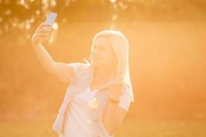 imagem de uma mulher sorridente de meia-idade tirando fotos de selfie em um parque de verão