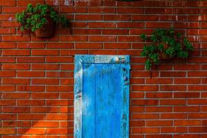 velha porta azul com caracóis e parede de tijolos foto