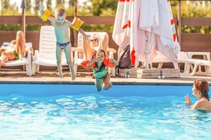 grupo de crianças pulando na piscina ao ar livre foto