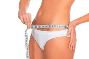ajuste a jovem medindo sua cintura, fundo branco foto