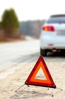 carro branco e um sinal de alerta de triângulo vermelho na estrada foto