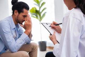 psicóloga profissional mulher conduzindo consulta e conversa com paciente homem asiático