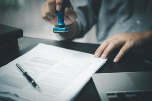 homem carimbando a aprovação de documentos bancários de finanças de trabalho ou de marketing de investimento na mesa. foto