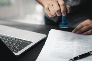 homem carimbando a aprovação de documentos bancários de finanças de trabalho ou de marketing de investimento na mesa. foto