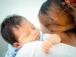 mãe amorosa carregando seu bebê recém-nascido adormecido no ombro em casa. retrato de mãe segurando filho bebê dormindo nas mãos. mãe abraçando sua filhinha de dois meses. foto
