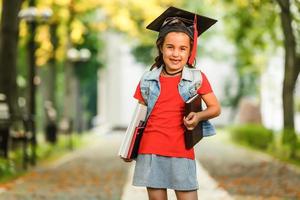 garoto de escola feliz graduado em chapéu de formatura olhando para cima foto