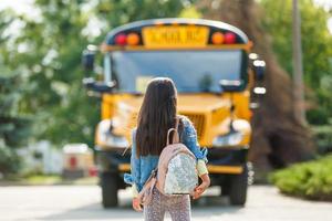 menina com mochila vai para ônibus escolar foto
