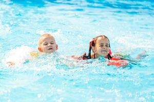 menino sorridente e menina nadando na piscina do parque aquático foto