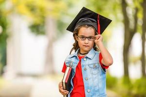 linda criança se formando segurando seu diploma e sorrindo foto