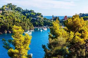 barcos de pesca ancorados na água no porto do mar da ligúria e mediterrâneo perto da costa da riviera di levante do parque nacional cinque terre costa com céu azul, vila de riomaggiore, ligúria, itália. foto