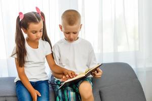 as crianças lêem um livro em casa foto