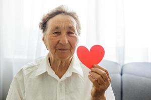 dia dos namorados, verão e conceito de pessoas idosas - retrato de mulher sênior sorridente com coração vermelho foto