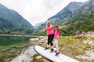 mãe e filha caminhando nas montanhas perto do lago itália foto