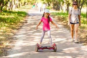 uma garotinha andando de patinete elétrico. transporte ecológico pessoal, giroscópio, roda de equilíbrio inteligente. transporte elétrico popular foto