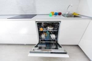 máquina de lavar louça aberta com pratos limpos na cozinha de casa foto