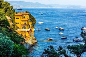 barcos de pesca ancorados na água no porto do mar da ligúria e mediterrâneo perto da costa da riviera di levante do parque nacional cinque terre costa com céu azul, vila de riomaggiore, ligúria, itália. foto