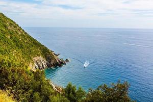 barcos de pesca ancorados na água no porto do mar da ligúria e mediterrâneo perto da costa da riviera di levante do parque nacional cinque terre costa com céu azul, vila de riomaggiore, ligúria, itália. foto