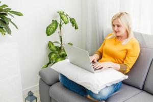 jovem mulher com laptop trabalha em casa foto